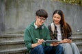 Two cheerful Asian college students using tablet on campus building outdoor stairs Royalty Free Stock Photo