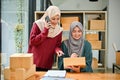 Two cheerful Asian Muslim female online shop sellers preparing shipping orders