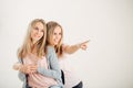 Two attrative sisters twins pointing over white background