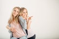 Two cheerful attrative sisters twins pointing over white background