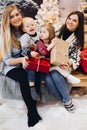 Two mothers sitting with cute kids and holding christmas presents. Royalty Free Stock Photo