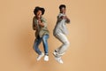 Two Cheerful Black Guys Pointing At Camera While Jumping Over Beige Background Royalty Free Stock Photo