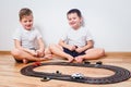 Two cheerful boys in white t-shirts play with children`s cars and a highway