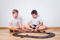 Two cheerful boys in white t-shirts start toy cars