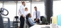 Two cheerful businessmen shaking hands while being in office together with their colleagues Royalty Free Stock Photo