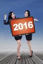 Two cheerful businesswomen hold numbers 2016