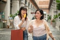 Two cheerful Asian female friends are enjoying popsicles while walking in the shopping mall Royalty Free Stock Photo