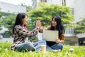 Two cheerful college students are giving each other a high five while sitting on the grass in a park Royalty Free Stock Photo