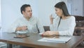 Two cheerful coworkers talking over coffee in a cafe