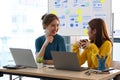 Two creative women talking each other while working together at modern office. Royalty Free Stock Photo