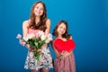 Two cheerful cute sisters holding bouquet of flowers and heart Royalty Free Stock Photo