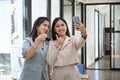 Two female business colleagues taking a selfie with smart phone at office. Royalty Free Stock Photo
