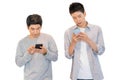 Two cheerful friends wear gray t-shirts standing isolated over white background, holding mobile phone.Couple of cool guys using Royalty Free Stock Photo