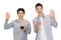 Two cheerful friends wear gray t-shirts standing isolated over white background, holding mobile phone.Couple of cool guys using Royalty Free Stock Photo