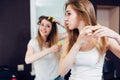 Two cheerful girlfriends putting their hair in curlers at home