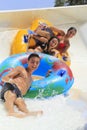 Two cheerful girls and boy drive with tube on the rafting slide