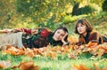 Two cheerful girls . Girl with her best friend. Two women in a park. Two beautiful teenage girls lying in the autumn