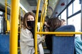 Two cheerful girls in protective masks in a city bus