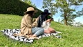 Two cheerful girls sitting on the grass using the mobile. Two happy female friends sitting on the grass with the phone Royalty Free Stock Photo