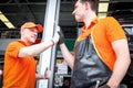 Two cheerful and happy worker men giving touching hands and hi five during working in garage automobile service center. car servic