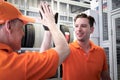 Two cheerful and happy worker men giving touching hands and hi five during working in garage automobile service center. car