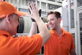 Two cheerful and happy worker men giving touching hands and hi five during working in garage automobile service center. car