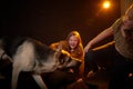 Two cheerful joyfull sisters having fun together and with big german shepherd dog in dark studio with black background