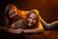 Two cheerful joyfull sisters having fun together in dark studio with black background