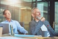 Two cheerful mature male coworkers sitting at meeting in the modern office