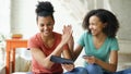 Two cheerful mixed race curly girlfriends shopping online with tablet computer and credit card at home Royalty Free Stock Photo