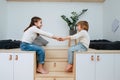 Two cheerful siblings sitting on wooden elevation holding hands