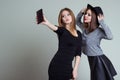 Two cheerful smiling girl girlfriends photographed on the phone, do selfie phone in the studio on a gray background Royalty Free Stock Photo