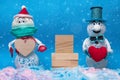 Two cheerful snowmen stand in the snow, between them there is a wooden pedestal for the inscription, valentine\'s day