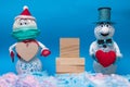 Two cheerful snowmen stand in the snow, between them there is a wooden pedestal for the inscription, valentine\'s day