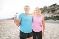 Two cheerful sporty active middle aged women smiling at camera together standing on the beach after workout training on Royalty Free Stock Photo