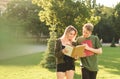 Two cheerful students checking homework in the park near the college campus. Couple of positive students reading books at the Royalty Free Stock Photo