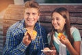 Two cheerful teenagers, girl and boy, eating pizza