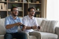 Two cheerful twins brothers playing online video game at home