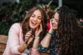 Two cheerful women listening music with cellphone and earphones and singing while sitting outdoor Royalty Free Stock Photo