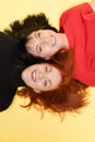 Two cheerful women smiling at camera. Two optimistic women with dark and red hair laughing lying on the floor.