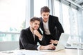 Two cheerful young businessmen using laptop on business meeting together Royalty Free Stock Photo