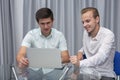 Two cheerful young businessmen working and using laptop on business meeting together Royalty Free Stock Photo