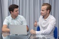 Two cheerful young businessmen working and using laptop on business meeting together Royalty Free Stock Photo