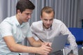 Two cheerful young businessmen working and using laptop on business meeting together Royalty Free Stock Photo