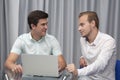 Two cheerful young businessmen working and using laptop on business meeting together Royalty Free Stock Photo