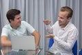 Two cheerful young businessmen working and using laptop on business meeting together Royalty Free Stock Photo