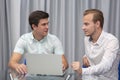 Two cheerful young businessmen working and using laptop on business meeting together Royalty Free Stock Photo