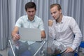 Two cheerful young businessmen working and using laptop on business meeting together Royalty Free Stock Photo