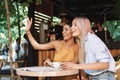 Two cheerful young girlfriends sitting at the cafe table Royalty Free Stock Photo