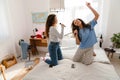 Two young girls holding brushes as microphones and singing songs on bed Royalty Free Stock Photo